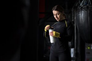 Mulher segurando uma garrafa com suplementos para ganho de massa muscular
